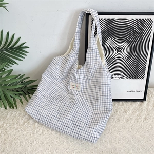 Detail shot of the blue checkered tote bag with a small colorful logo patch