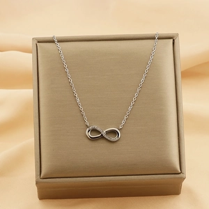 Detail view of a silver infinity pendant with small crystals on champagne silk fabric