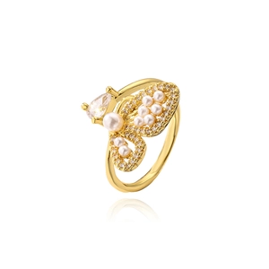 Macro detail of 18K gold butterfly ring with inlaid pearls and zircon on white background