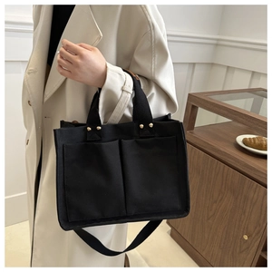 Détail du sac fourre-tout en toile noire avec deux poches et bandoulière réglable