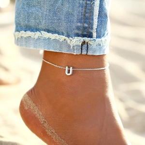 Detailed macro shot of a silver stainless steel anklet with a capital U letter pendant
