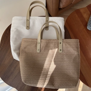 Detailed view of woven canvas tote bags with leather handles on a rustic wooden table