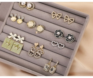 Detailed view of assorted stud and drop earrings organized in a gray velvet jewelry tray