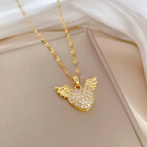 Detail of gold heart pendant with angel wings and clear rhinestones on silk