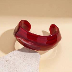 Detailed macro view of an organic deep ruby red resin bangle on a textured stone base