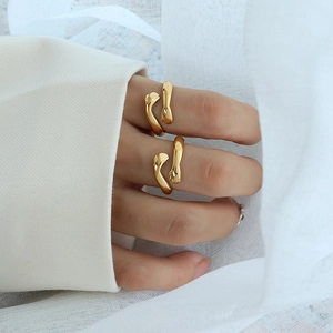 Minimalist gold hug ring with unique double hand design on white fabric background