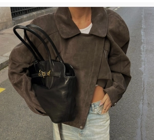 Close-up of a dark coffee suede biker jacket with belt and a black leather tote bag