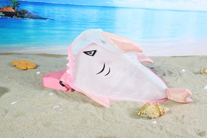 Pink cartoon shark mesh beach bag with shell accessories on a sunny sandy seaside