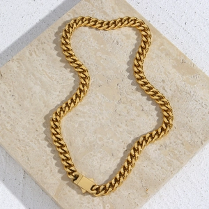 Golden chunky Cuban chain necklace with rectangular clasp on beige marble surface