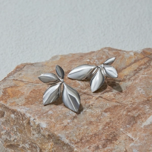 Macro shot of silver leaf earrings on natural stone showing fine metallic texture