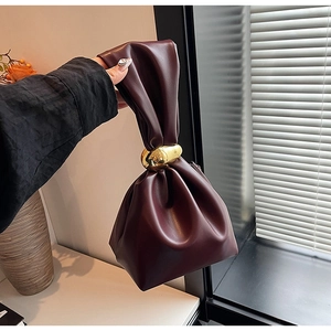 Macro shot of dark wine red bucket bag with pleated texture and gold metal ring handle