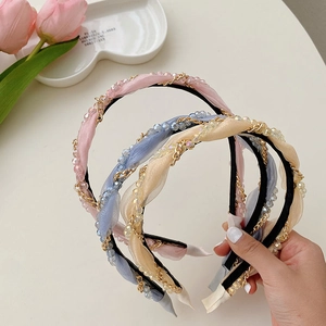 Detail of woven fabric headbands with gold chains and pearls in pink, blue, and beige