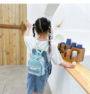 Detail of child wearing a blue sequin backpack with bunny ears and bow decoration