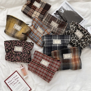 Flat lay of vintage plaid and leopard print cosmetic bags on a white textured fabric