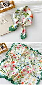 Detail of floral silk scarf featuring pink blossoms and a dark green border edge