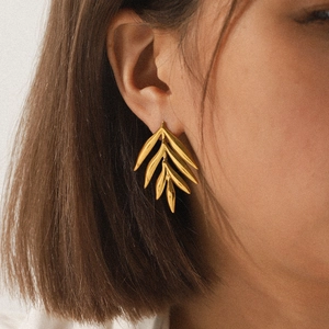 Close-up of 18K gold leaf shaped earring worn by a model for a luxury aesthetic