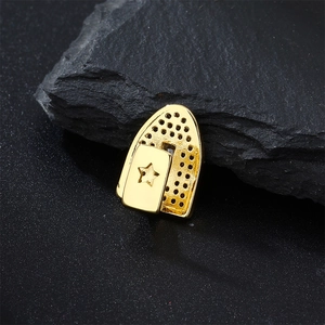 Macro shot of gold-plated single tooth grillz with star cutout and micro-pave setting
