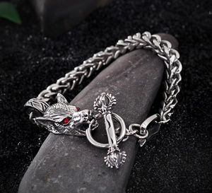 Close-up of silver wolf head steel bracelet with red gem eyes on a stone