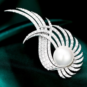 Détail macro d'une broche ailée élégante avec perle blanche et zircons sur satin vert