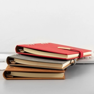 A5 premium leather binder notebooks in red, dark gray, and brown with metallic rings