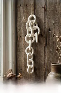 Detail of white ceramic chain wall hanging with interlocking rings on wood background