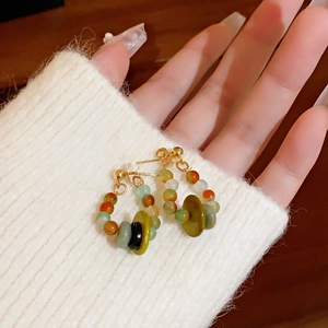 Close-up of handmade beaded drop earrings with colorful round beads and gold hooks