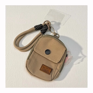 Detail of beige canvas mini wallet with front pocket, zipper, and thick rope lanyard
