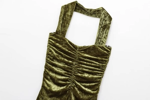 Detailed flat lay of olive green velvet dress with intricate pleated bodice textures