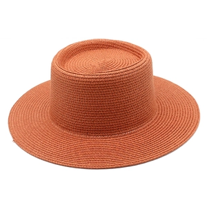 Detailed texture of burnt orange straw sun hat with wide brim and flat top design