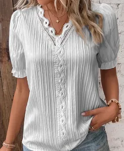 Detailed close-up of white summer blouse featuring lace V-neckline and pleated texture