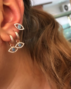 Close-up of rose gold Evil Eye hoop earrings and stud with blue crystals on model