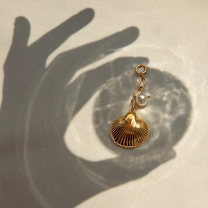 Pendentif coquillage doré élégant avec perle pour bikini sur fond artistique abstrait