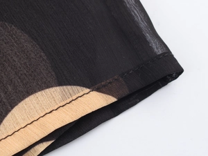 Détail du tissu en mousseline noire à pois beige montrant des coutures de qualité