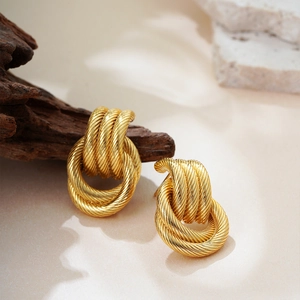 Macro shot of gold multi-layered twisted rope textured hoop earrings on a stone base