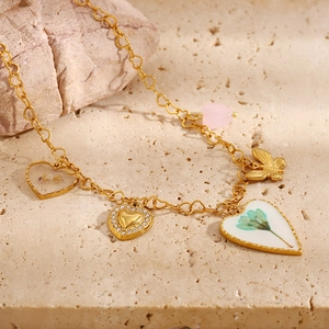 Detail of 18K gold heart pendant with resin dried flowers and rhinestone charms