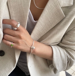 Close-up of irregular sterling silver ring and beaded jewelry worn with beige linen suit