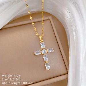 Détail d'un pendentif croix dorée avec cristaux sur soie blanche dans une boîte à bijoux