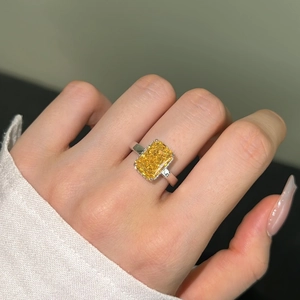 Macro shot of rectangular yellow gemstone ring with four-prong silver band setting