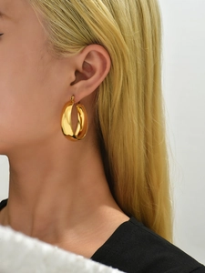 Close-up of model wearing thick golden 18K gold plated stainless steel hoop earrings
