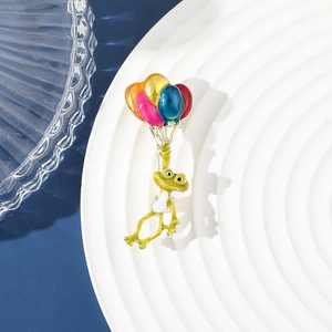 Détail macro de la broche émaillée grenouille verte avec ballons colorés sur assiette