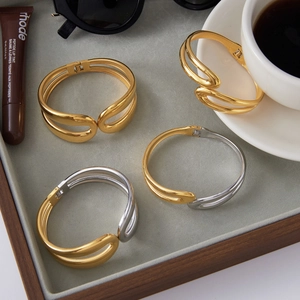 Polished 18K gold stainless steel double-layer wavy bangle shown on a grey velvet tray