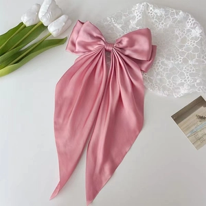 Close-up of pink satin bow hair clip with long ribbons and elegant silk texture