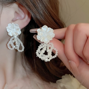 Boucles d'oreilles fleur en acrylique ivoire avec perles portées par un mannequin
