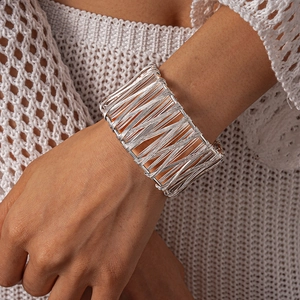 Detail of silver woven wire wrap cuff bracelet on model with white knitwear