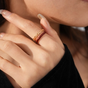 Detailed view of vintage gold chain ring and brown enamel band worn on a finger
