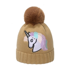 Dettaglio ricamo unicorno e pompon in finta pelliccia marrone su berretto in maglia kaki