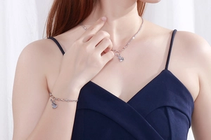 Close-up of violin pendant necklace and bracelet set on model with silver O-chain