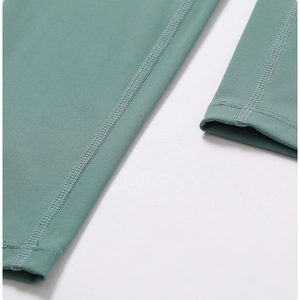 Detailed macro view of high-density flatlock stitching on green quick-dry yoga pants