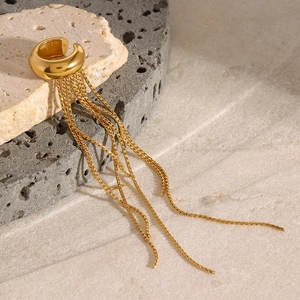 Detail of gold tassel ear cuff with multiple fine chains resting on a natural stone base