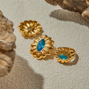 Macro view of gold flower earrings and ring set with blue marquise zircon stones